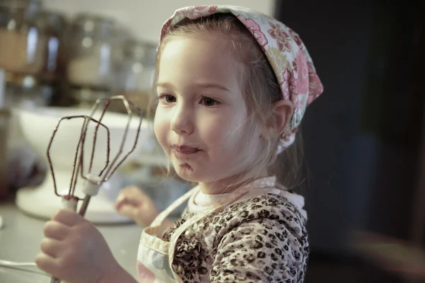 Mała dziewczynka lizanie czekolady wyłączony mikser trzepaczka — Zdjęcie stockowe