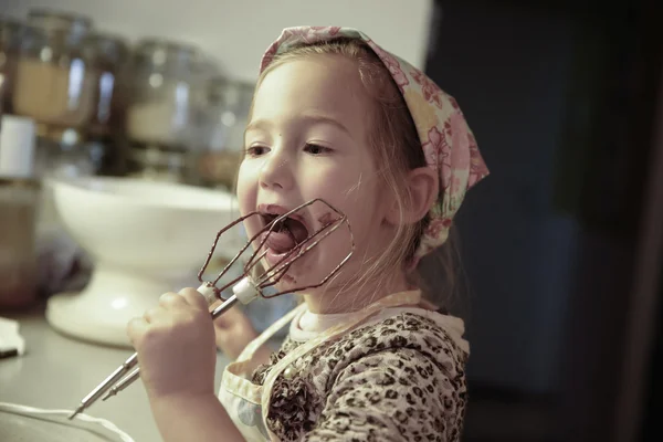 Μικρό κορίτσι γλείφει σοκολάτα από το μίξερ beater — Φωτογραφία Αρχείου