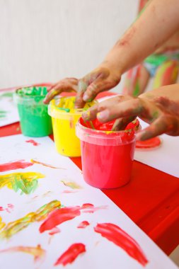 Child dipping fingers in washable finger paints