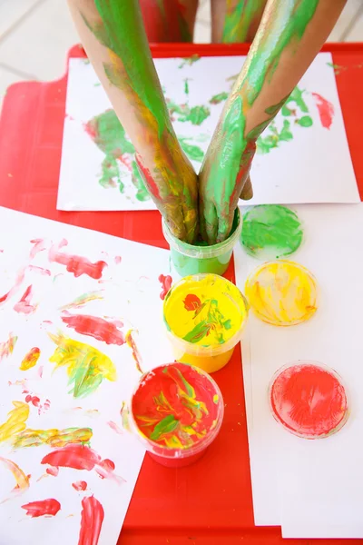 Child dipping fingers in washable finger paints — Stock Photo, Image