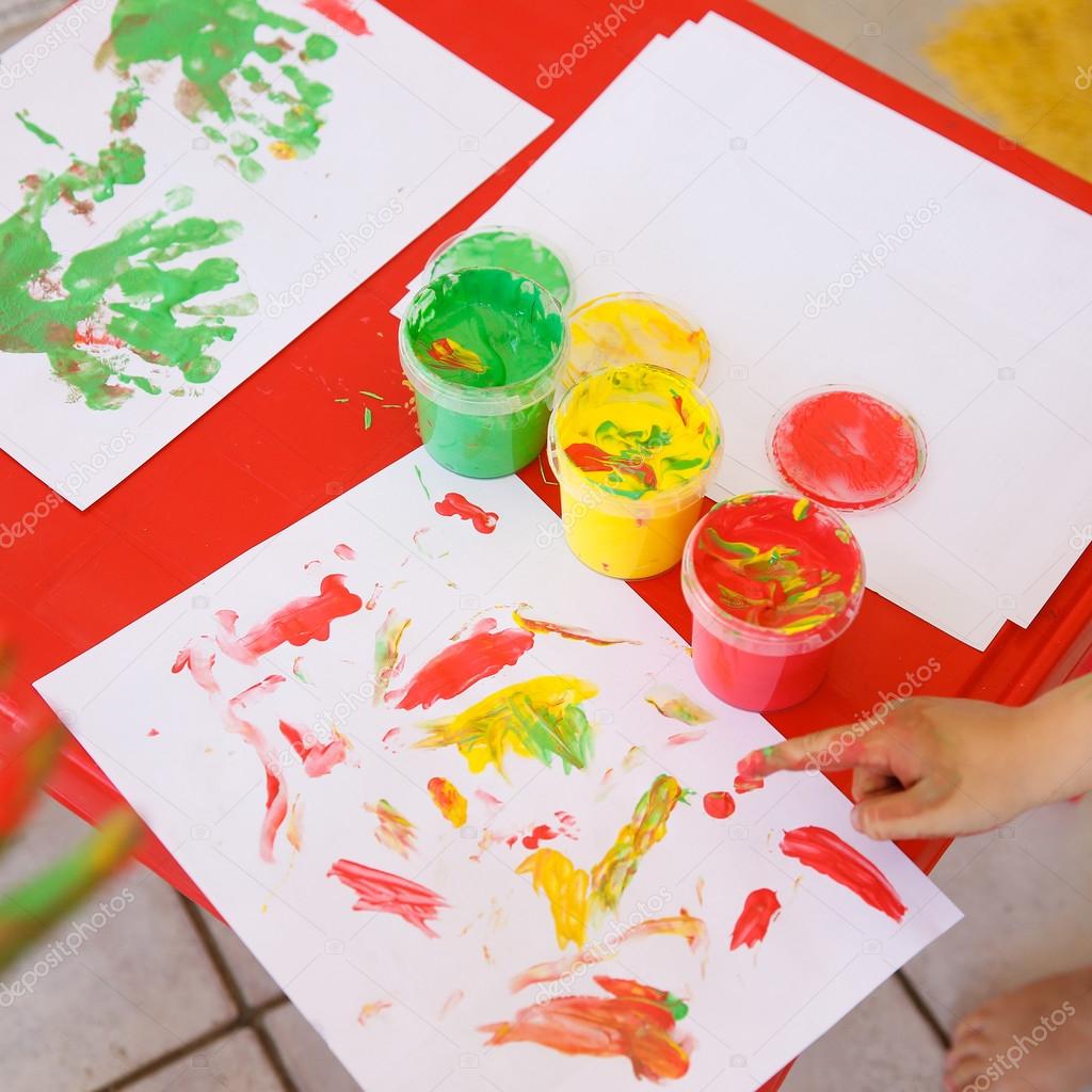 Child painting a drawing with finger paints