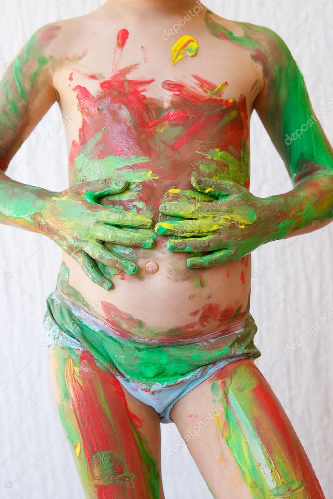Child body painting himself with finger paints