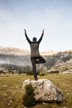 Man practicing yoga, performing a tree pose 