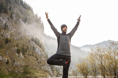 Man practicing yoga, performing a tree pose 