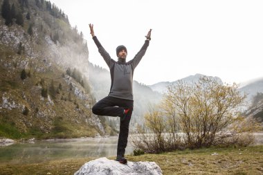 Man practicing yoga, performing a tree pose 