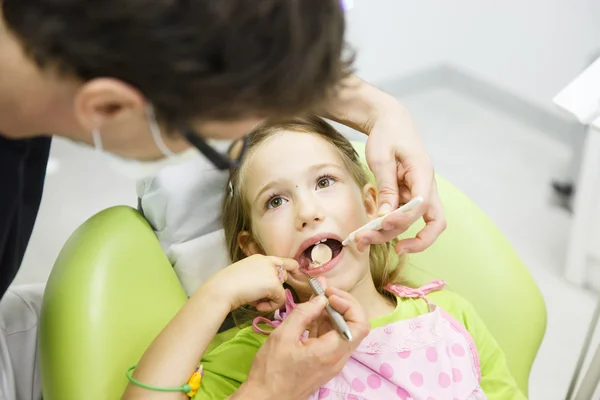 Маленька дівчинка сидить на стоматологічному стільці — стокове фото