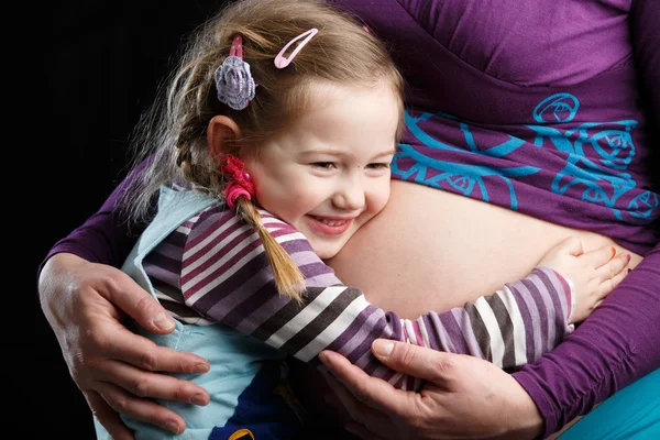Girl embracing pregnant belly — Stock Photo, Image