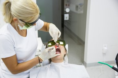 Dentist using a modern diode dental laser clipart