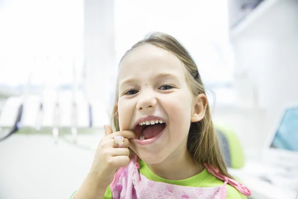 Menina mostrando seus dentes de leite saudáveis no consultório odontológico — Fotografia de Stock