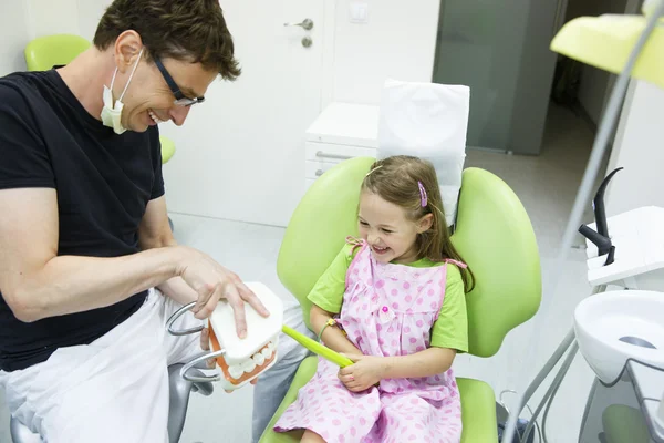 Girl in dentists chair tooth-brushing a model — Stock Photo, Image