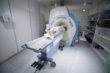 MR scanner in a hospital, with patient being scanned clipart