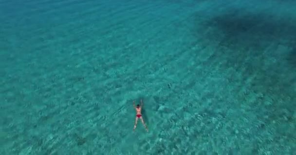 Foto aérea de una mujer, nadando en aguas marinas frescas y sorprendentemente turquesas, disfrutando de verano, sol y arena . — Vídeos de Stock