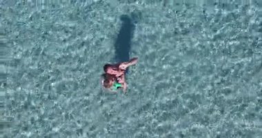 Yaz tatilinde güzel ve egzotik turkuaz deniz sularında eğlenen anne ve kızının drone'u iterken çekilmiş havadan çekilmiş fotoğrafı.