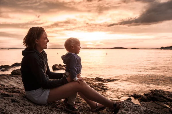 Ibu dan anak duduk di pantai berbatu, bersenang-senang — Stok Foto