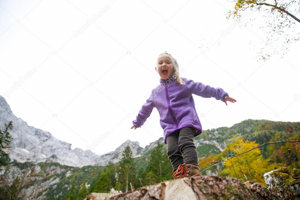 Triumphant little girl celebrating after climbing a rock