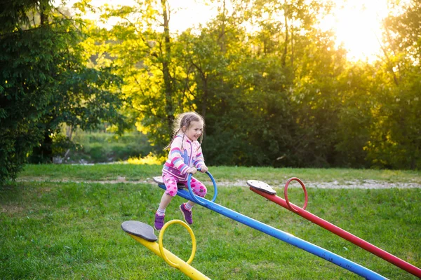 Joyeux petite fille jouer, monter annonce vers le bas sur une balançoire — Photo