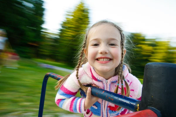 Kleines Mädchen lächelt auf einem bewegenden Karussell — Stockfoto