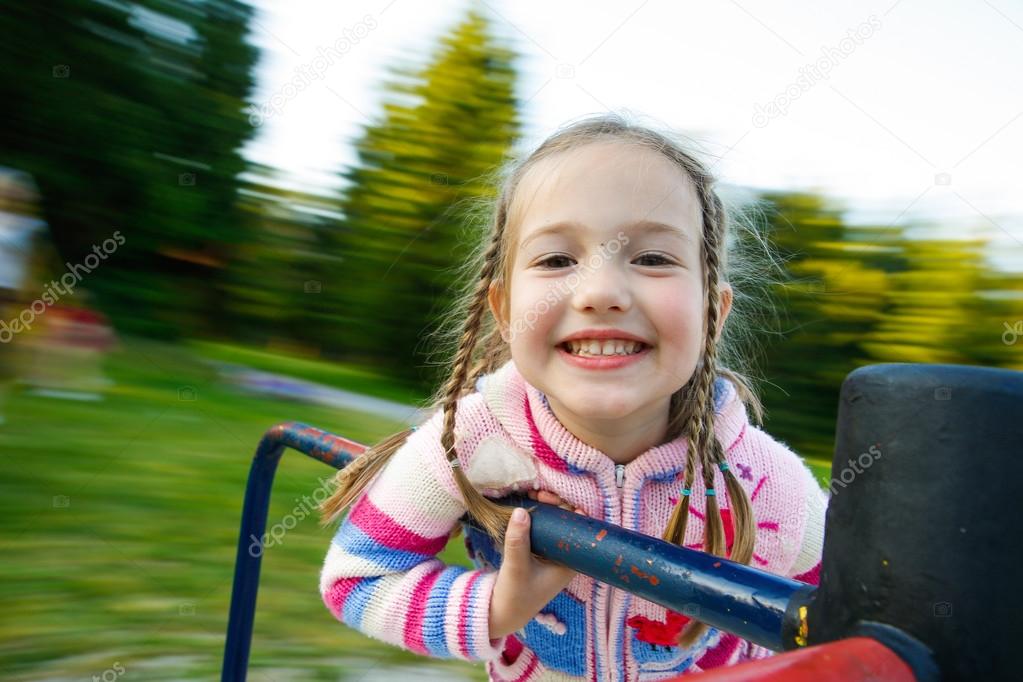 Little girl smiling on a moving merry-go-round