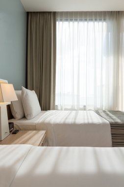 Beyaz yastık, çarşaf ve perde ile yatak odası