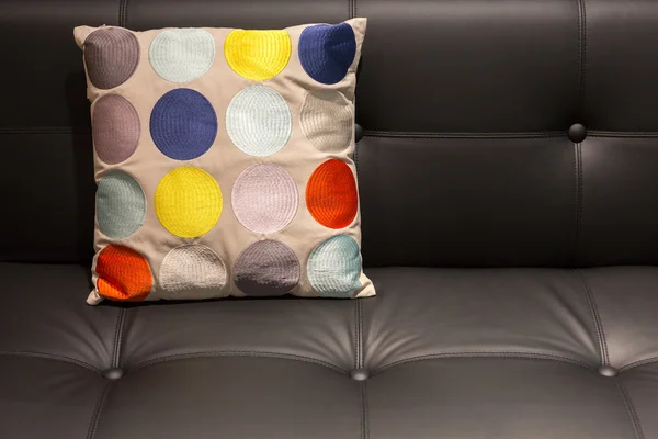 Colorida almohada punteada en un sofá de cuero negro — Foto de Stock