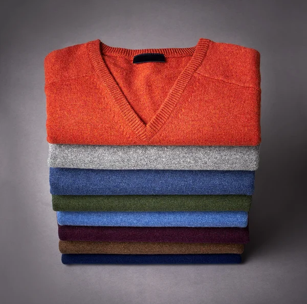 Pilha de suéter em um fundo cinza — Fotografia de Stock