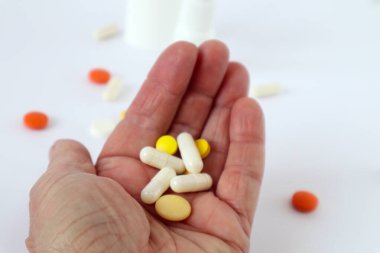 Yaşlı bir adamın elinde renkli haplar ve ampuller, yakın plan.