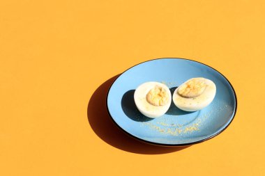 İki parça tavuk yumurtası mavi bir tabakta, sarı arka planda, mesaj için yer var.