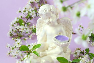 Mumlu alçı beyaz melek, pastel arka planda kiraz çiçeği dalları, yakın plan, bokeh