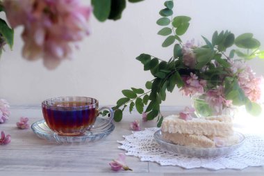 Günaydın kavramı. Hafif arka planda pembe akasyalı bir buket çay, bokeh.