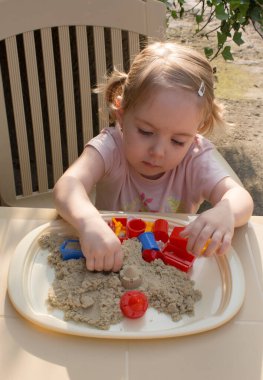 Çocuk kinetik kum kullanarak el hareketlerini geliştirir.