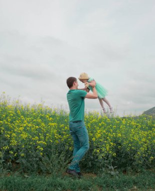 Kolza tarlasında yürüyen kız ve baba.