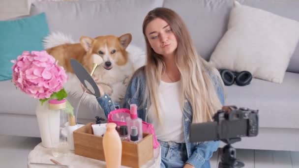 Atractiva chica adolescente con su lindo perro Vlogging mientras hace un maquillaje. Adolescente chica conducta remota enseñanza a maquillaje durante el blogueo. — Vídeos de Stock