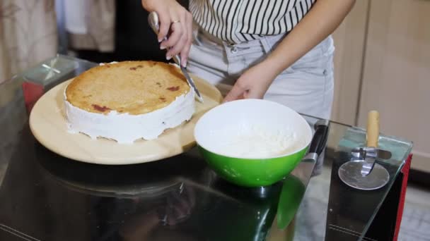 Kvinnliga händer att sätta grädde på en svamp tårta för hand med hjälp av pallete kniv. — Stockvideo