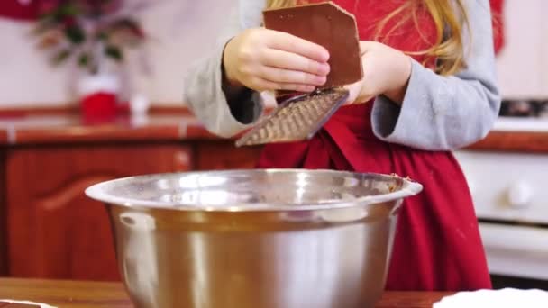 Крупним планом руки дівчини шеф-кухар натирає шоколад на тертці в миску . — стокове відео