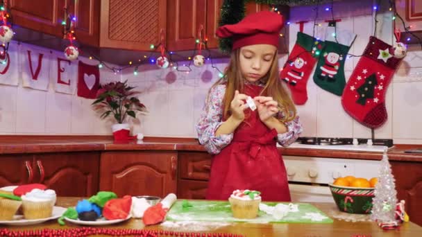 Ein fröhliches Küchenmädchen dekoriert einen Cupcake — Stockvideo