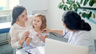 Stetoskop kullanan kadın doktor. Annesiyle birlikte hastaneyi ziyaret eden sağlıklı ve tatlı kızın kalbini dinle. Kadın Doktor Muayene Çocuğu.