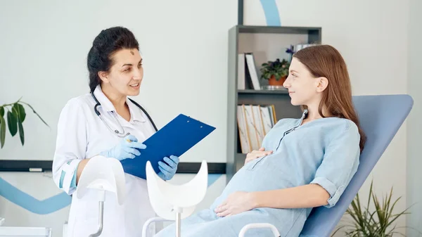 Glückliche Schwangere besuchen den Frauenarzt in der Medizinischen Klinik. Ärztinnen untersuchen schwangere junge Mutter, um ihre Gesundheit zu überprüfen. Teenager-Schwangerschaft. Beratung Schwangere in Klinik. — Stockfoto