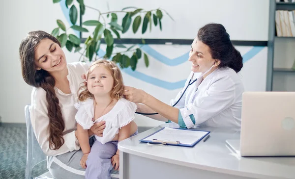 Kvinna läkare Pediatriker Använda stetoskop Lyssna på hjärtat av lycklig hälsosam söt Kid Girl vid läkarbesök med mor på sjukhuset. Kvinnlig doktor undersöker barn. — Stockfoto