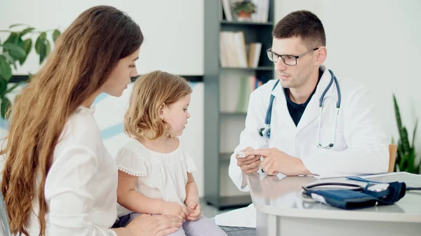 Férfi orvos gyerekorvos, aki tablettákat ad a Beteg Kölyöknek. Egy anya gyerekkel a gyermekorvosnál. Beszélgetés egy orvossal a konzultáción egy megbeszélés során.. — Stock Fotó