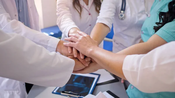 Primer plano de los trabajadores médicos apilan las manos sobre la mesa para recibir apoyo en el trabajo. Equipo de Médicos del Hospital Moderno. Espíritu de equipo moderno en Clinic. — Foto de Stock