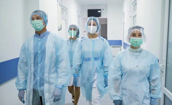 Koruyucu Takım Elbiseli Doktorlar Takımı. Tıbbi İşçiler Modern Hastanenin Koridorunda Maskeli Yürüyüş. Covid-2019 ile savaşıyorum. Klinikteki doktorlar.