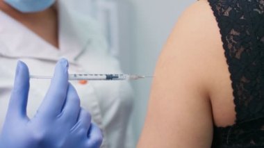 COVID-19 aşısı. Klinikte bir hastaya aşı enjekte eden bir tıp hemşiresi. Doktor, tedavi olarak şırınga ve şırınga ile şırınga kullanıyor..