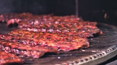 Barbekü ızgara et. Sulu domuz kaburgaları ızgaranın ızgarasında kızartılıyor, Şef kaburgaları Spatula ile çeviriyor..