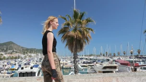 Μια όμορφη ξανθιά κοπέλα στο skateboard το καλοκαίρι ζεστή μέρα μπροστά στη θάλασσα — Αρχείο Βίντεο