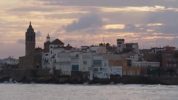 O horizonte da cidade ao pôr-do-sol perto da água. Algumas nuvens no céu. — Vídeo de Stock