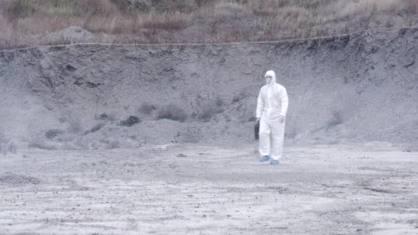 Labortechniker in Maske und Chemikalienschutzanzug läuft mit Werkzeugkiste auf trockenem Boden durch giftigen Rauch — Stockvideo