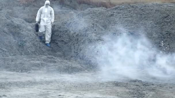 Labortechniker in Maske und Chemikalienschutzanzug läuft mit Werkzeugkiste auf trockenem Boden durch giftigen Rauch — Stockvideo