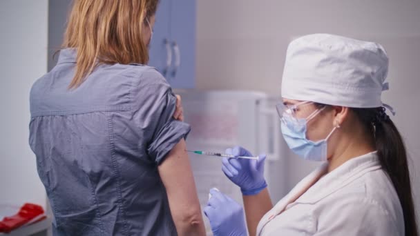 Vakcína COVID-19. Zdravotní sestra, která podává pacientovi na klinice očkovací látku. Doktor používá podkožní jehlu a injekční stříkačku k aplikaci léků jako léčbu. — Stock video
