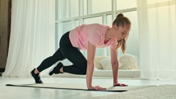 Ung Kvinna Göra Plank Flexing Ben Motion i dynamisk hemma. Sportig passform flicka gör Fitness Aerobic övningar hemma. Home Workout hälsosam livsstil. — Stockvideo