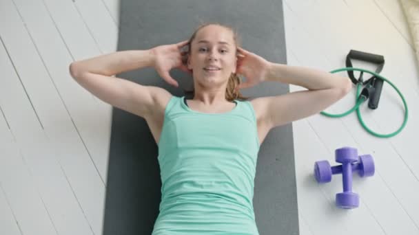 Vedere de sus a unei fete tinere atractive care lucrează, făcând exerciții pentru abdomene pe mașina de fitness acasă, duce un stil de viață sănătos . — Videoclip de stoc